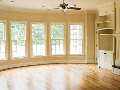 Empty, clean living room with timber floors and a row of tall windows