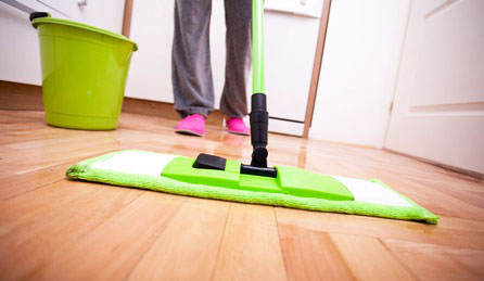 Flat mop and green bucket being used to clean a timber floor